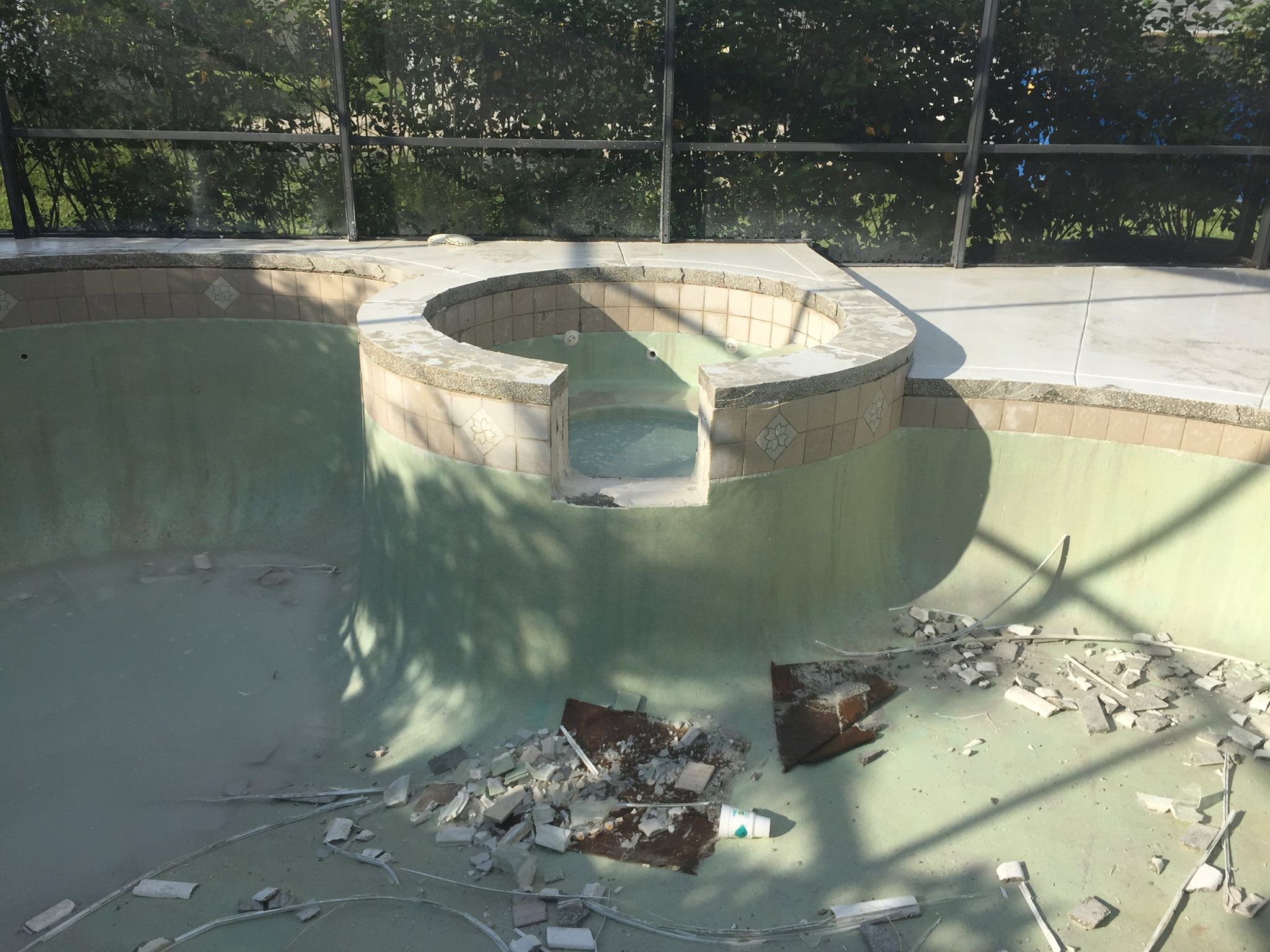 Empty swimming pool under renovation with debris, showcasing Kristi's Pool Service expertise in pool maintenance and repair.