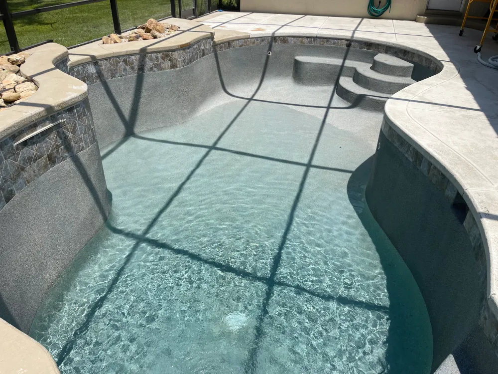 Modern backyard pool with clear water, stone accents, and curved steps, maintained by Kristi's Pool Service.
